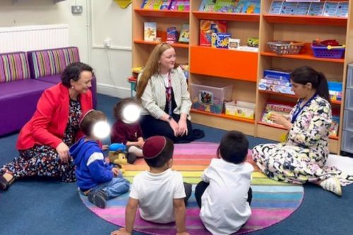 Education Minister on a rug with several children